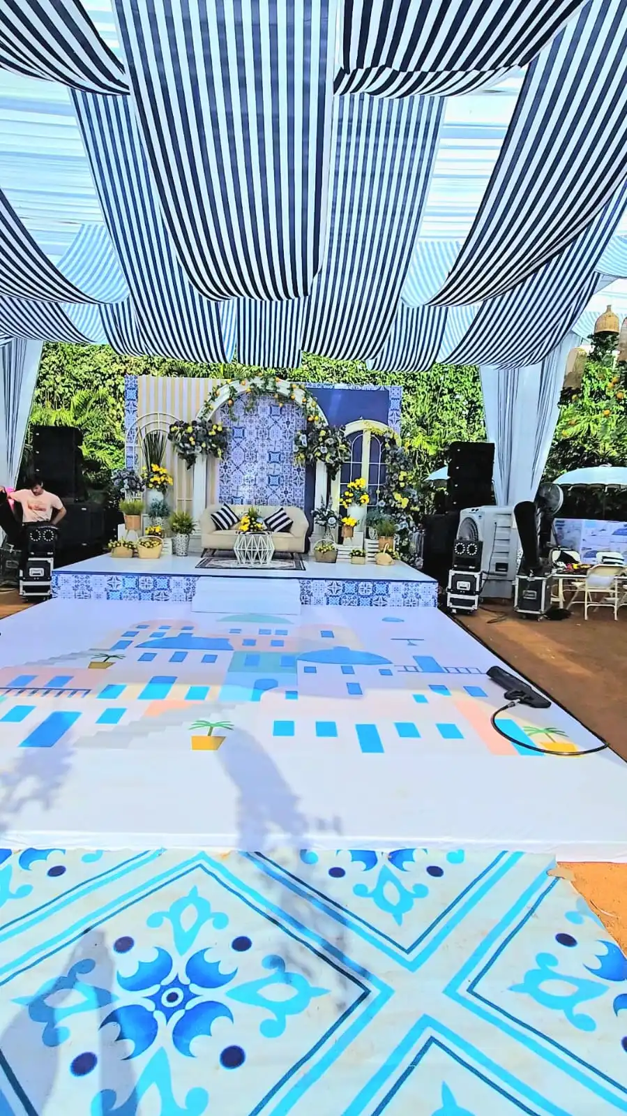 Blue and white tiled stage with striped canopy and floral backdrop