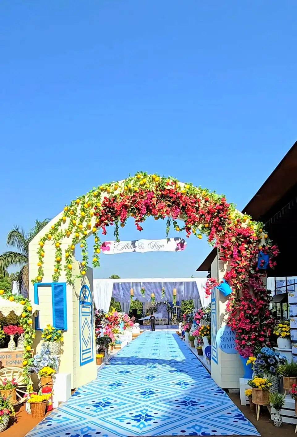 Floral entrance arch with lemons and bougainvillea over a blue-tiled walkway
